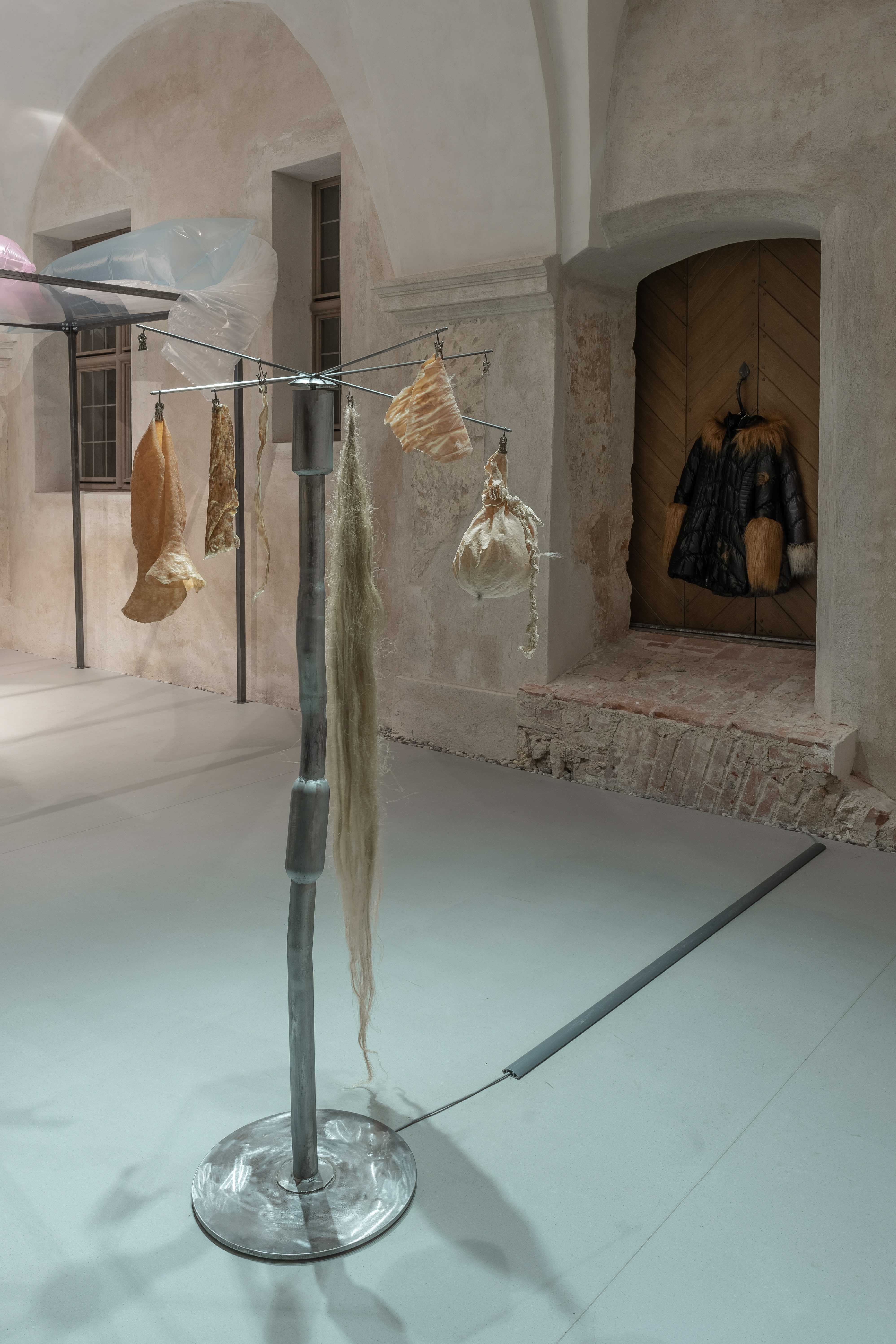 KamilÄ PikelytÄ, Vita Sintetika, 2024, found mufflers, steel, latex, collagen from rabbit skin, soap, linen fibre, snake exuvia, silicon.