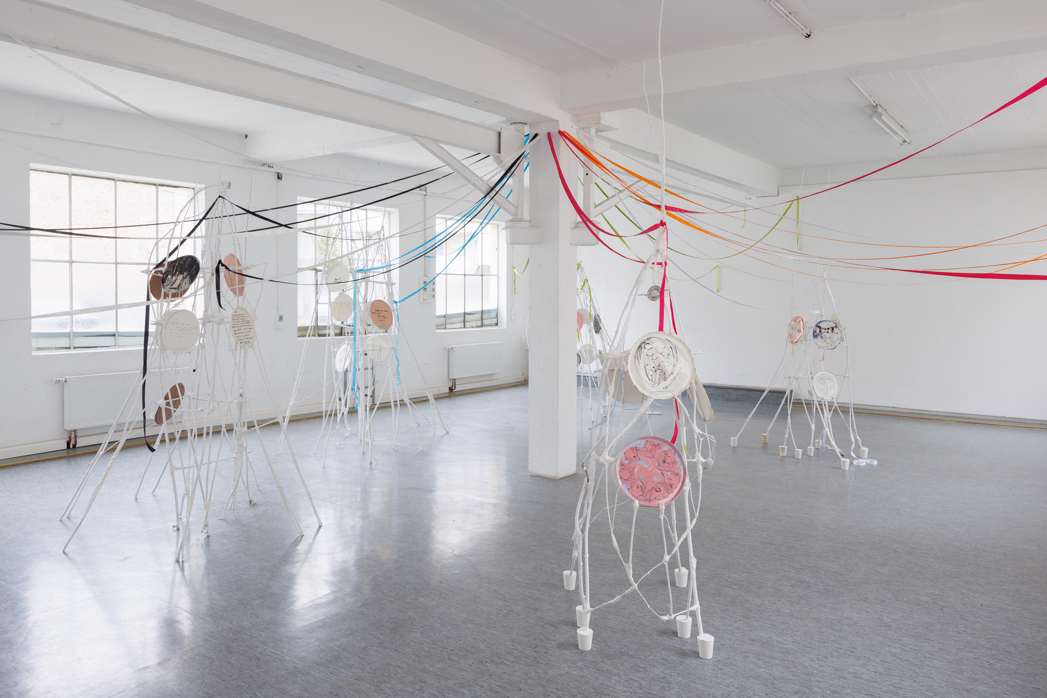 Anna Łuczak, Sophie Schmidt, “Brutality of Spring,” 2024, installation view (porcelain plates, white paint, wood ribbon, metal plate holders, cutlery, make up).