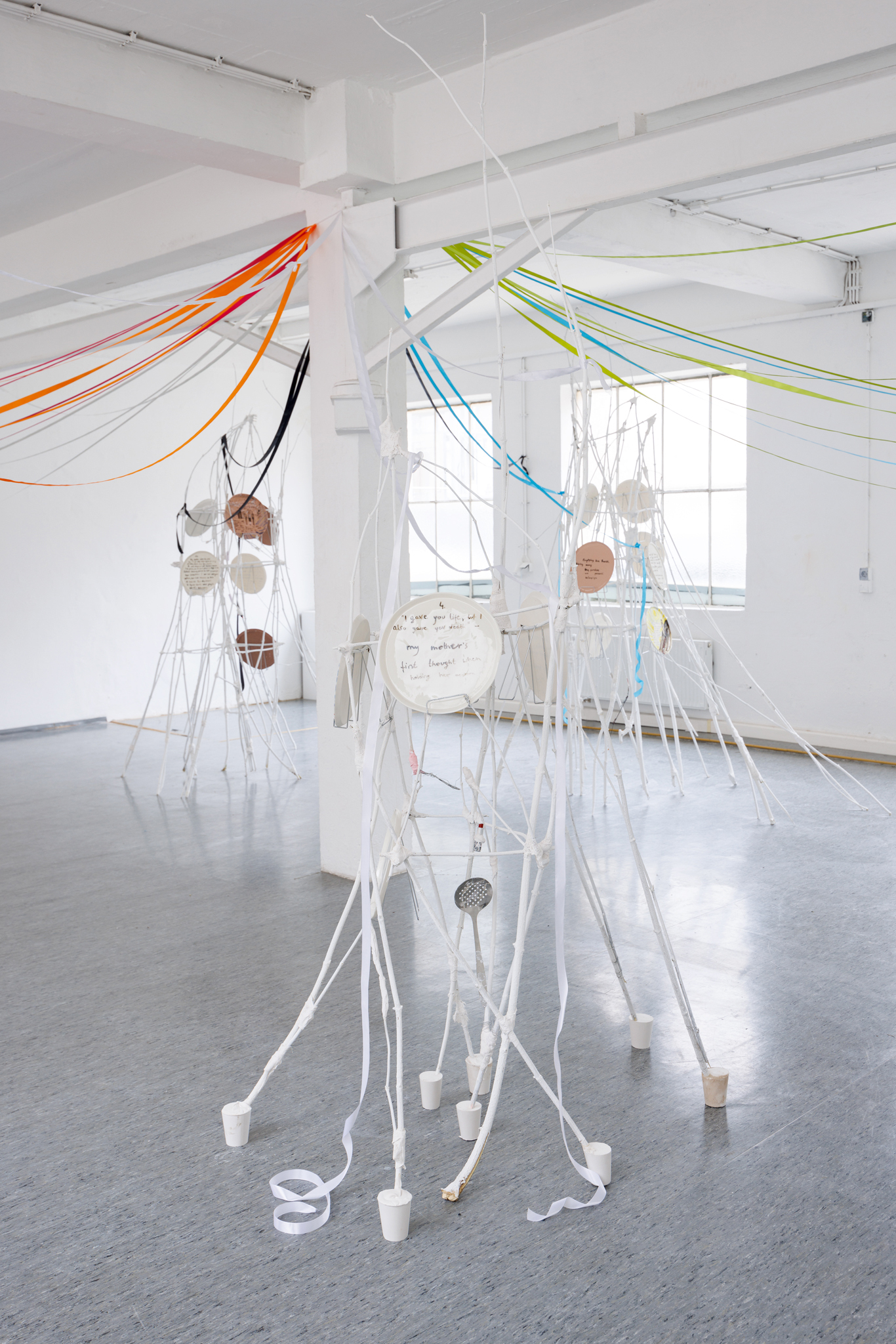 Anna Łuczak, Sophie Schmidt, “Brutality of Spring,” 2024, installation view (porcelain plates, white paint, wood ribbon, metal plate holders, cutlery, make up).
