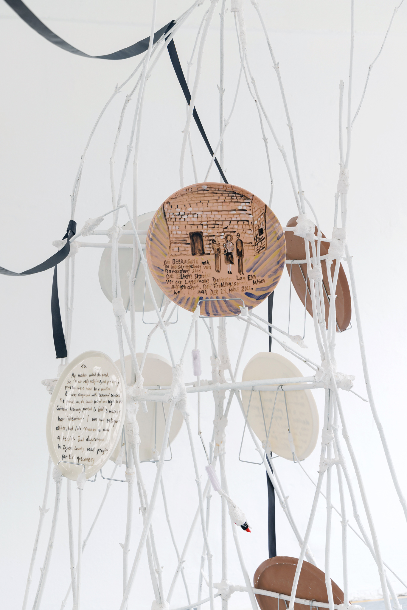 Anna Łuczak, Sophie Schmidt, “Brutality of Spring,” 2024, detail (porcelain plates, white paint, wood ribbon, metal plate holders, cutlery, make up).