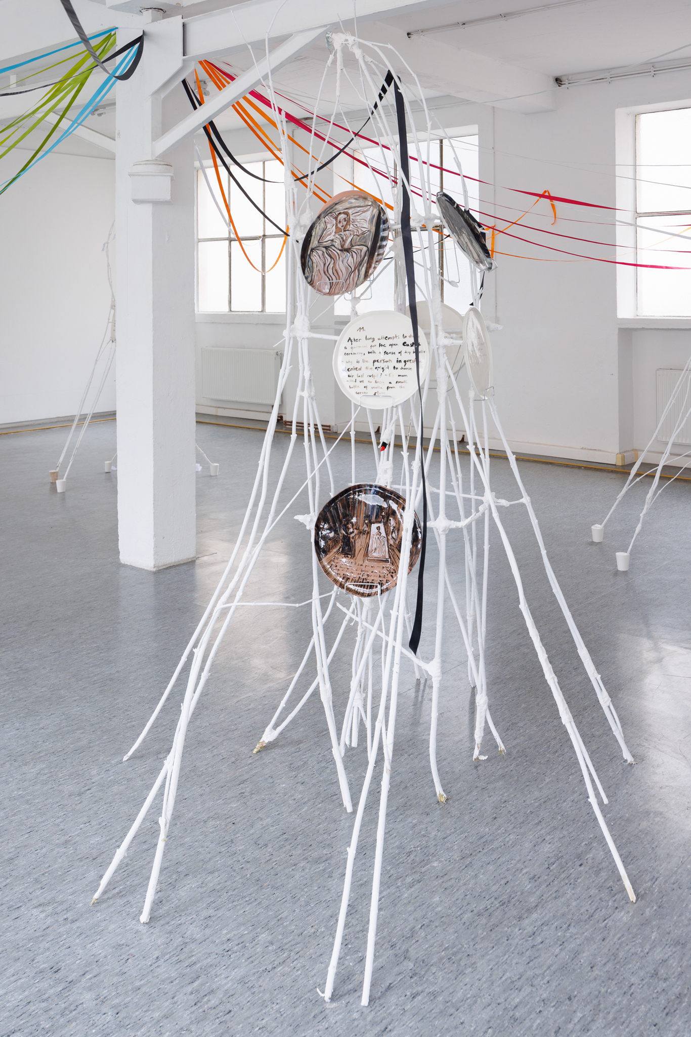 Anna Łuczak, Sophie Schmidt, “Brutality of Spring,” 2024, installation view (porcelain plates, white paint, wood ribbon, metal plate holders, cutlery, make up).