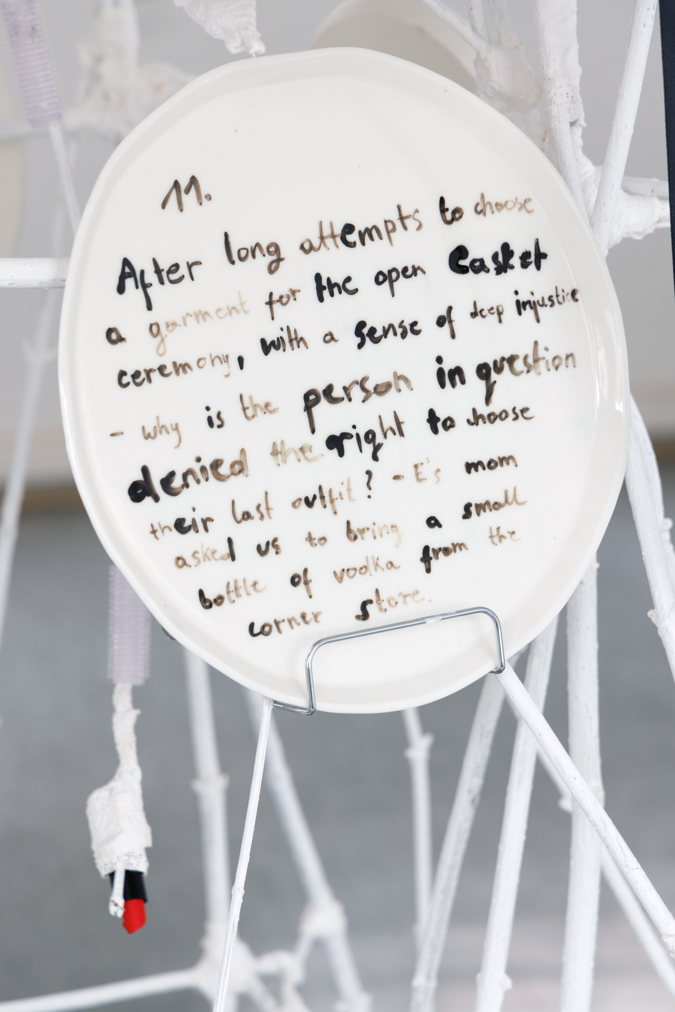 Anna Łuczak, Sophie Schmidt, “Brutality of Spring,” 2024, detail (porcelain plates, white paint, wood ribbon, metal plate holders, cutlery, make up).