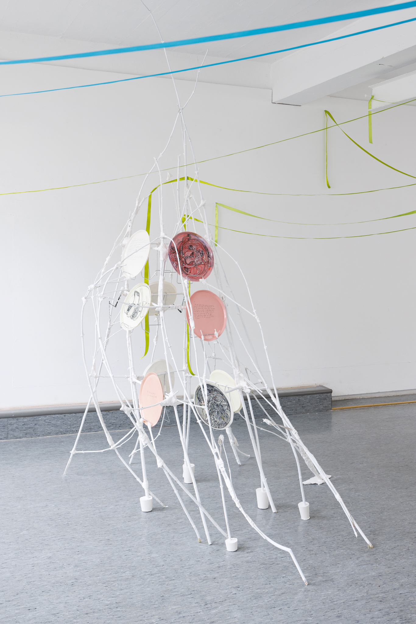 Anna Łuczak, Sophie Schmidt, “Brutality of Spring,” 2024, installation view (porcelain plates, white paint, wood ribbon, metal plate holders, cutlery, make up).