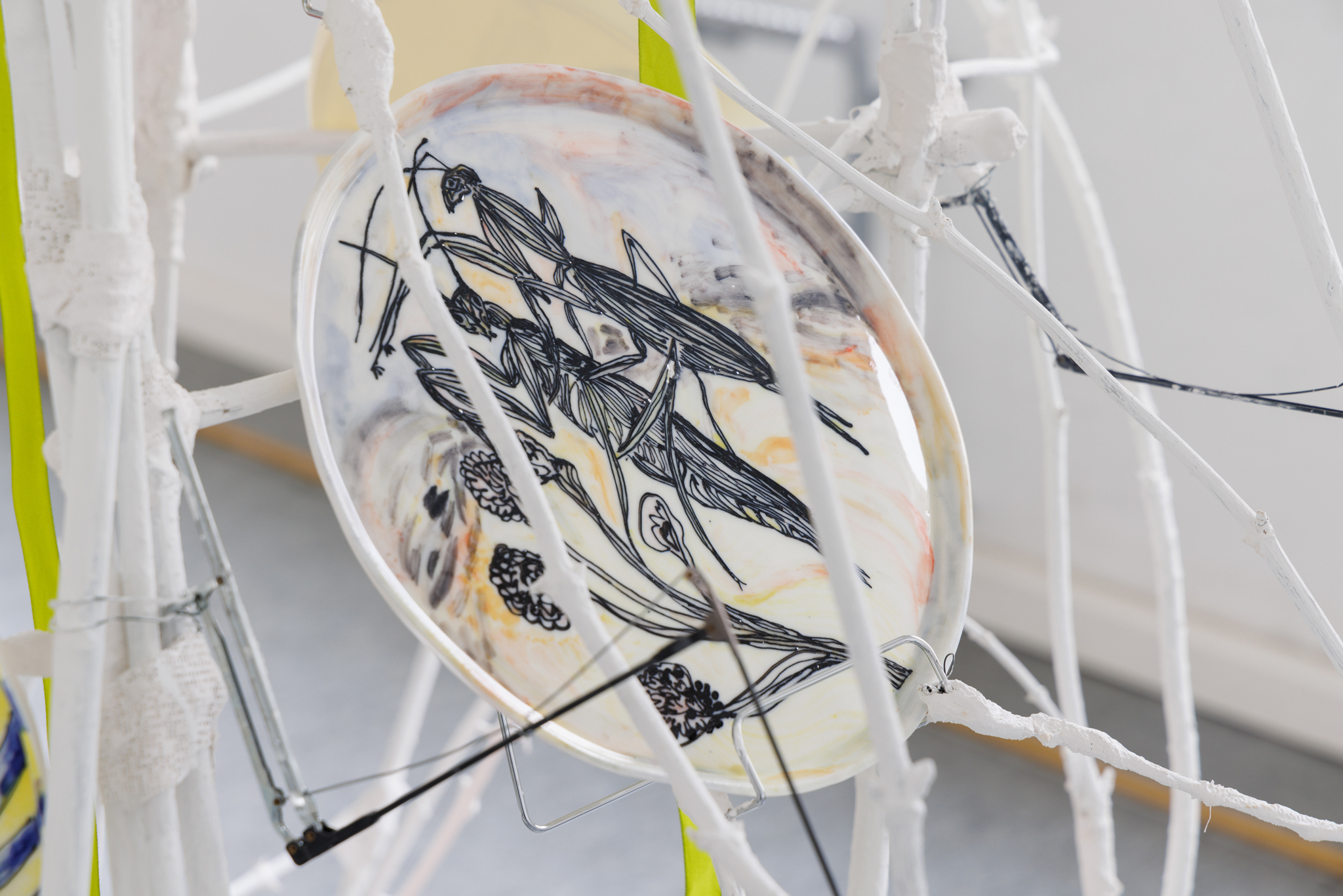 Anna Łuczak, Sophie Schmidt, “Brutality of Spring,” 2024, detail (porcelain plates, white paint, wood ribbon, metal plate holders, cutlery, make up).