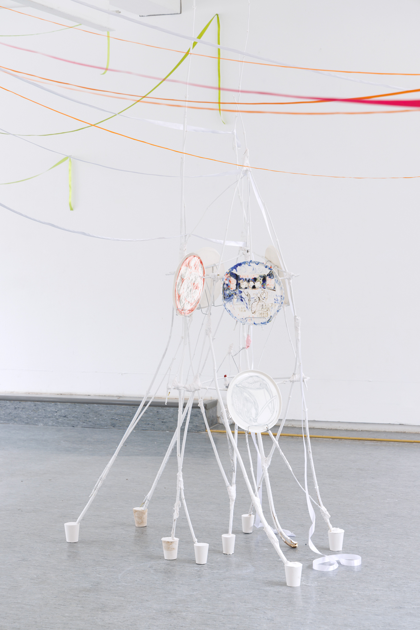 Anna Łuczak, Sophie Schmidt, “Brutality of Spring,” 2024, installation view (porcelain plates, white paint, wood ribbon, metal plate holders, cutlery, make up).