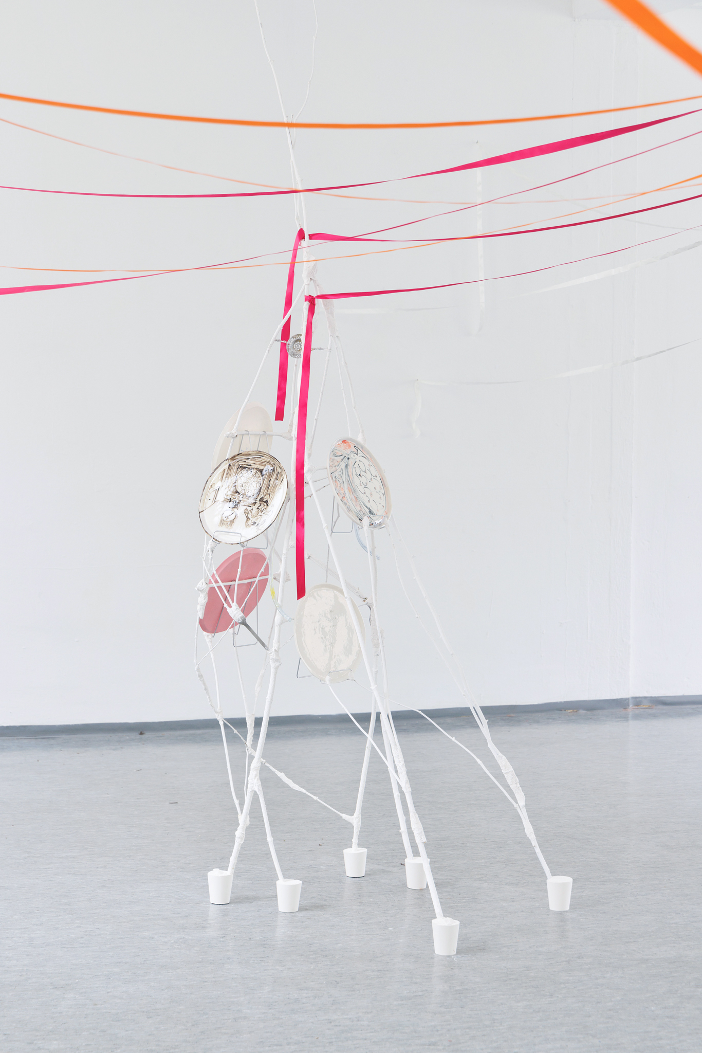 Anna Łuczak, Sophie Schmidt, “Brutality of Spring,” 2024, installation view (porcelain plates, white paint, wood ribbon, metal plate holders, cutlery, make up).