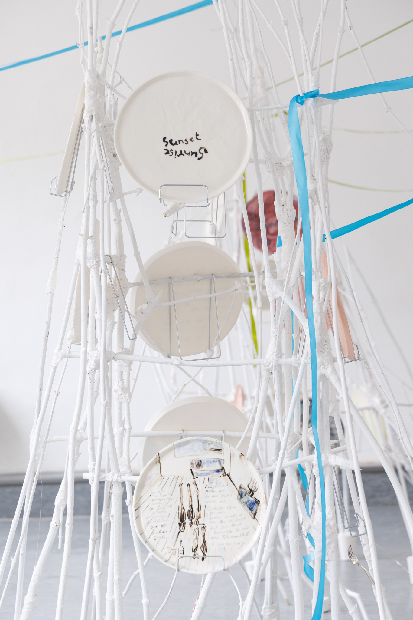 Anna Łuczak, Sophie Schmidt, “Brutality of Spring,” 2024, detail (porcelain plates, white paint, wood ribbon, metal plate holders, cutlery, make up).