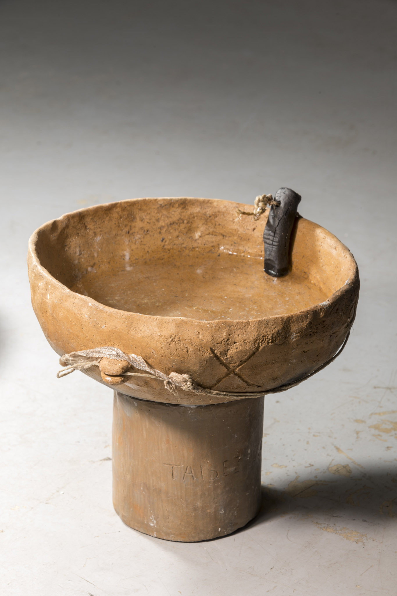 Clovis Maillet, MM, 2025. Soil from the Caffarella Park, vegetal wax, pieces of clothes from a victim of femicide, plants, water from the Loire River, holy water, solar fountains. 80 x 80 x 25 cm.