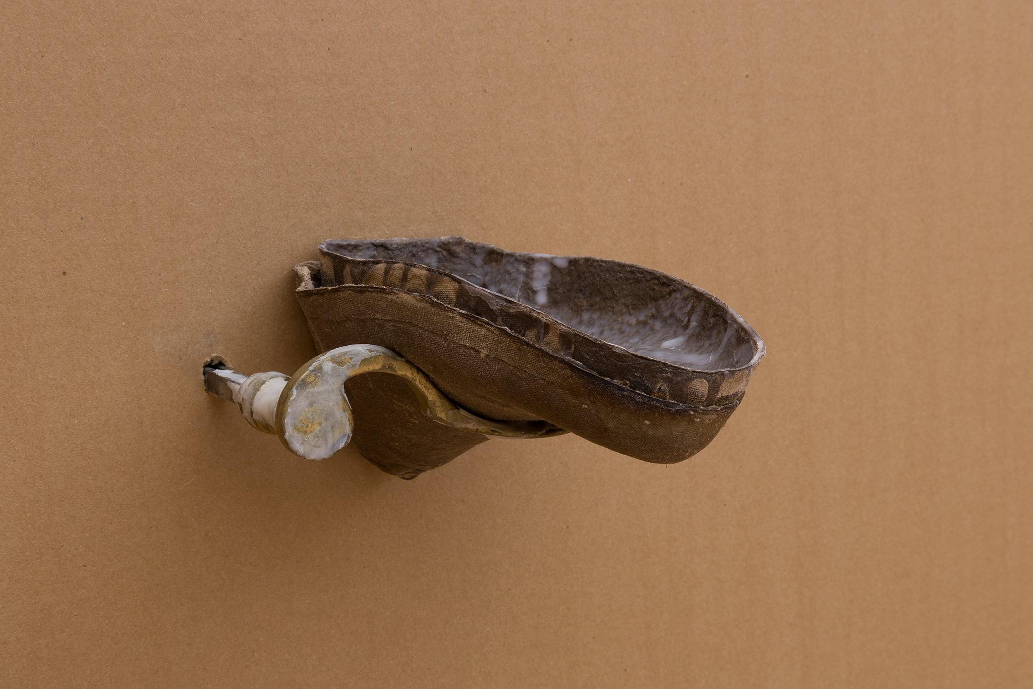 All Of My Shoes (Tempo), 2025. Old brass door handle with traces of air-dry porcelain; cardboard shoe insert with beeswax, raw cardboard shoe insert, piezo microphones, water dripping system. 19 x 11 x 14 cm