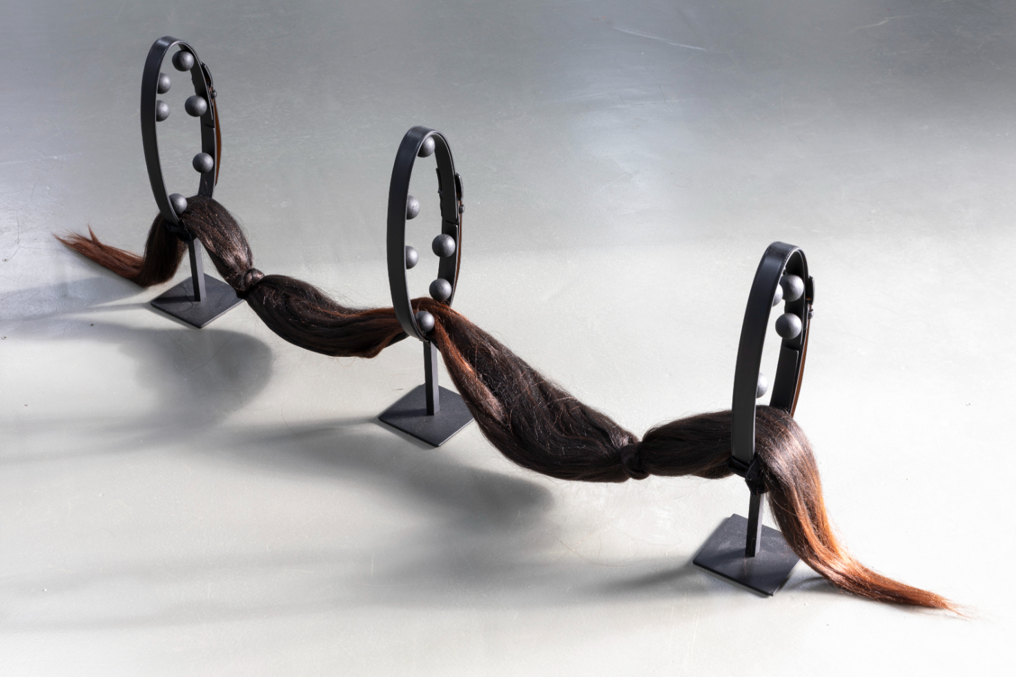 Yeşim Akdeniz, Loop, 2025. Metal, foam, paint, belt, hair. 160x13x25 cm.