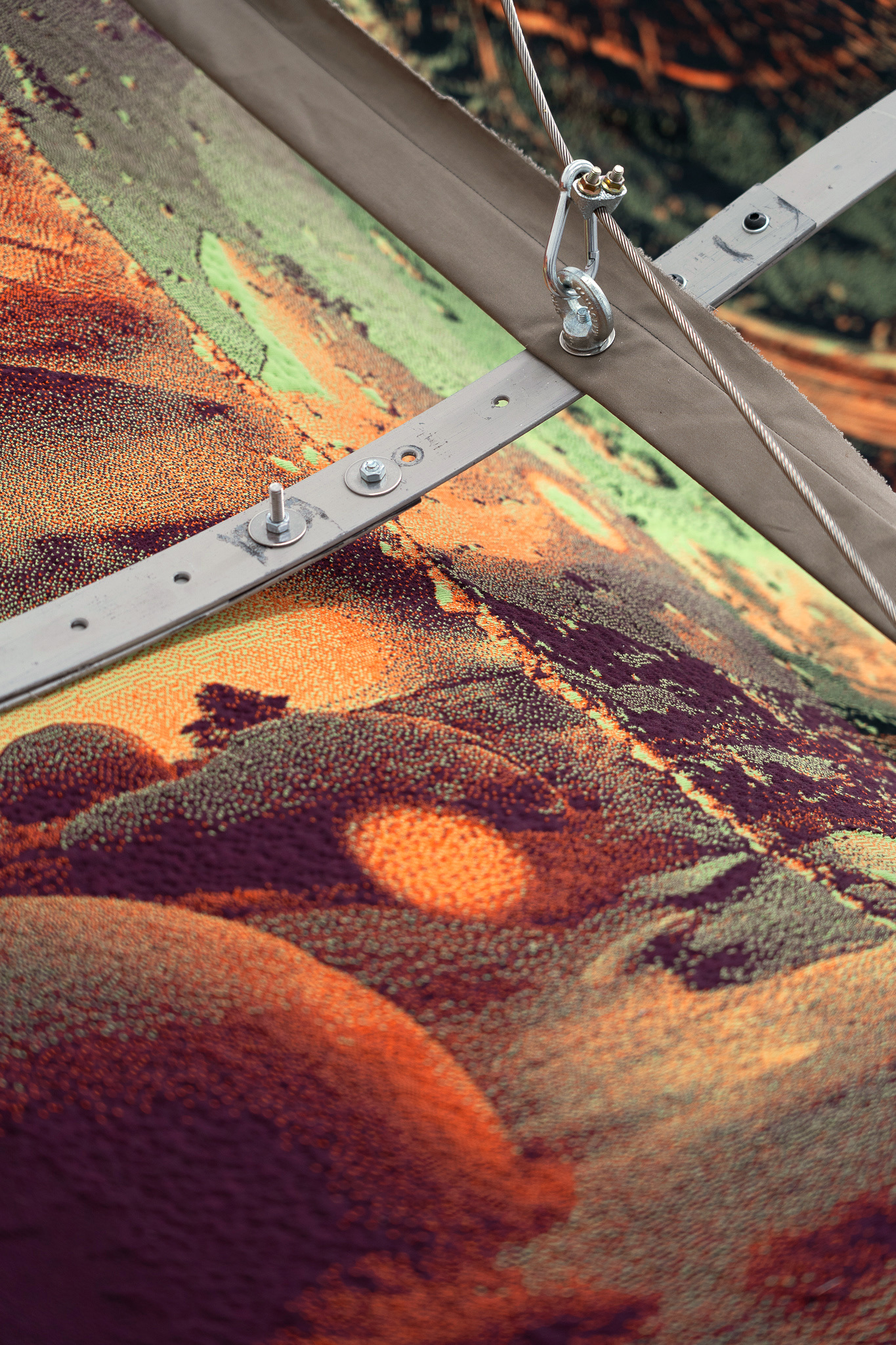 Nicola Arthen - Reading A Reflection (2025); Collage from generated images, machine-knitted wool, cotton and filling yarn, steel rig, C-prints, wooden carts with engravings, work pants, lights, sensors (760x160x145cm), courtesy of the artist and Platform