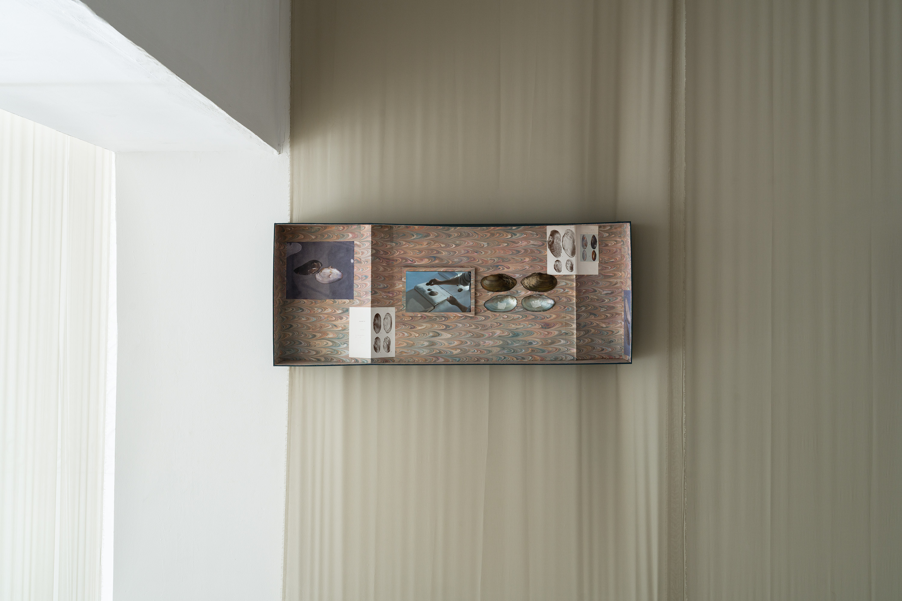 Boîte N°1 (Musée), 2025. Cardboard, marbled paper, binding fabric, photographs, 126 x 50 x 18 cm. they built up the picture by Caroline Reveillaud, 16.01-28.02.26, at Komplot, Brussels. Image Lola Pertsowsky  