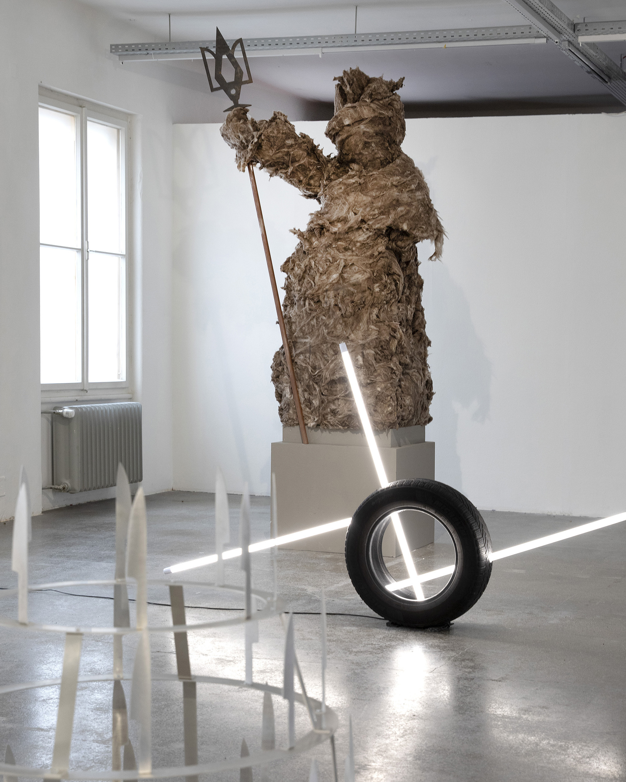 Softshell Archipel, exhibition view with Bögdana Kosmina's Neptunia, 2026 Mineral wool, aluminium, wood 280 × 100 × 100 cm; Vasco Costa, Driven by Numbers, 2025 Car tyres, LED neon tubes Each 120 × 60 × 60 cm