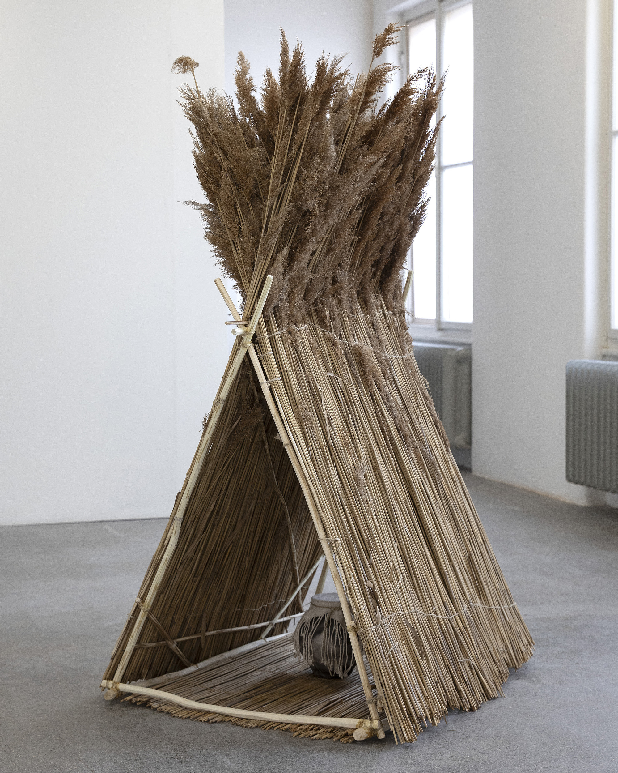 Jason Bunton, How It Might Have Been, 2025 Wood, hemp and linen cord, reed, beeswax, ceramic urn 90 × 90 × 190 cm