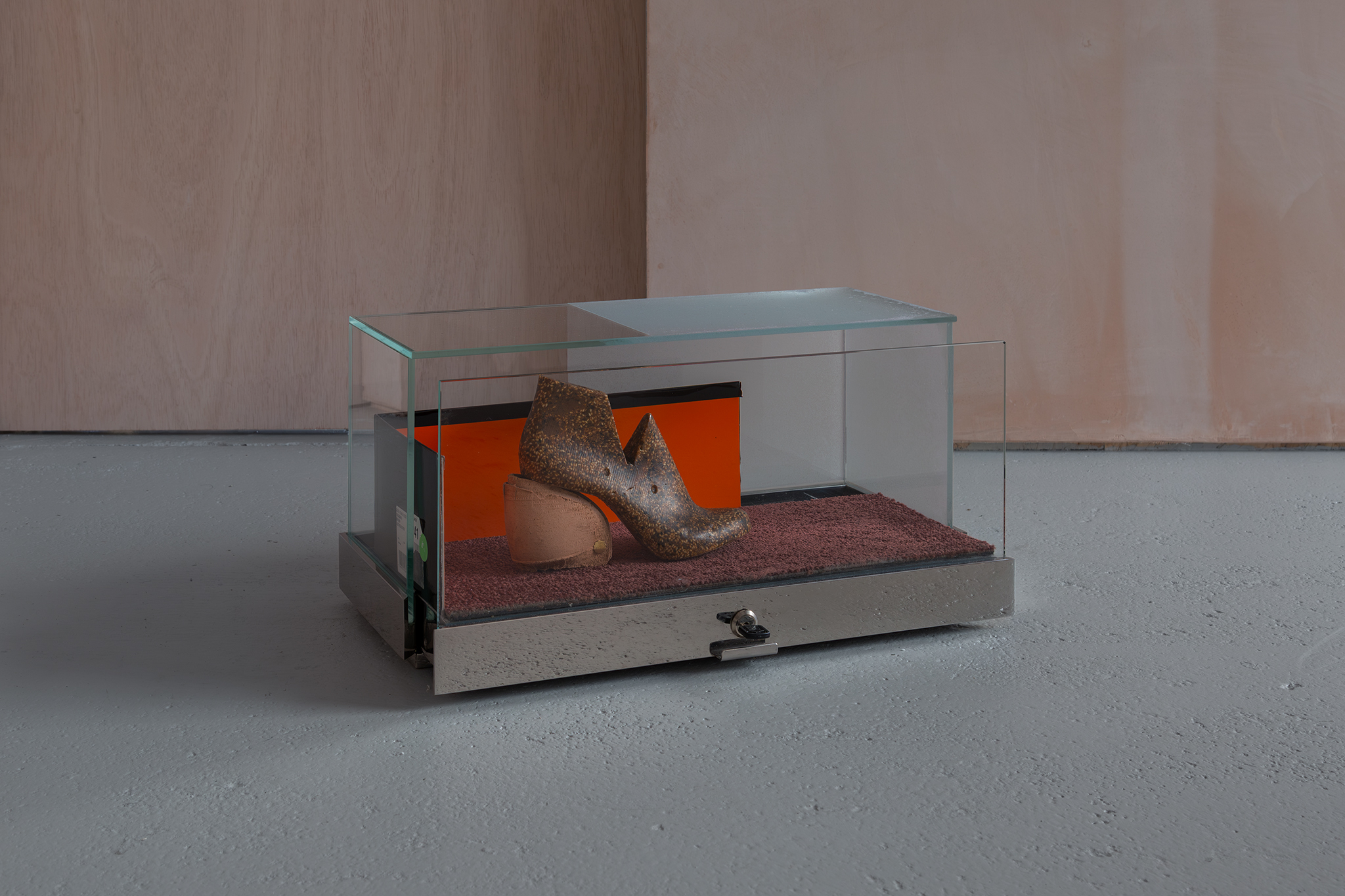 Maquette for an arid vision, 2026. Sesame in pine rosin and beeswax binder, carpet tile, cardboard shoe box and glass, frosted vinyl and stainless steel vitrine. S.A.D lamp, tulip ply and brown tape. Light programmed at the ratio of 2:1. Alia Hamaoui