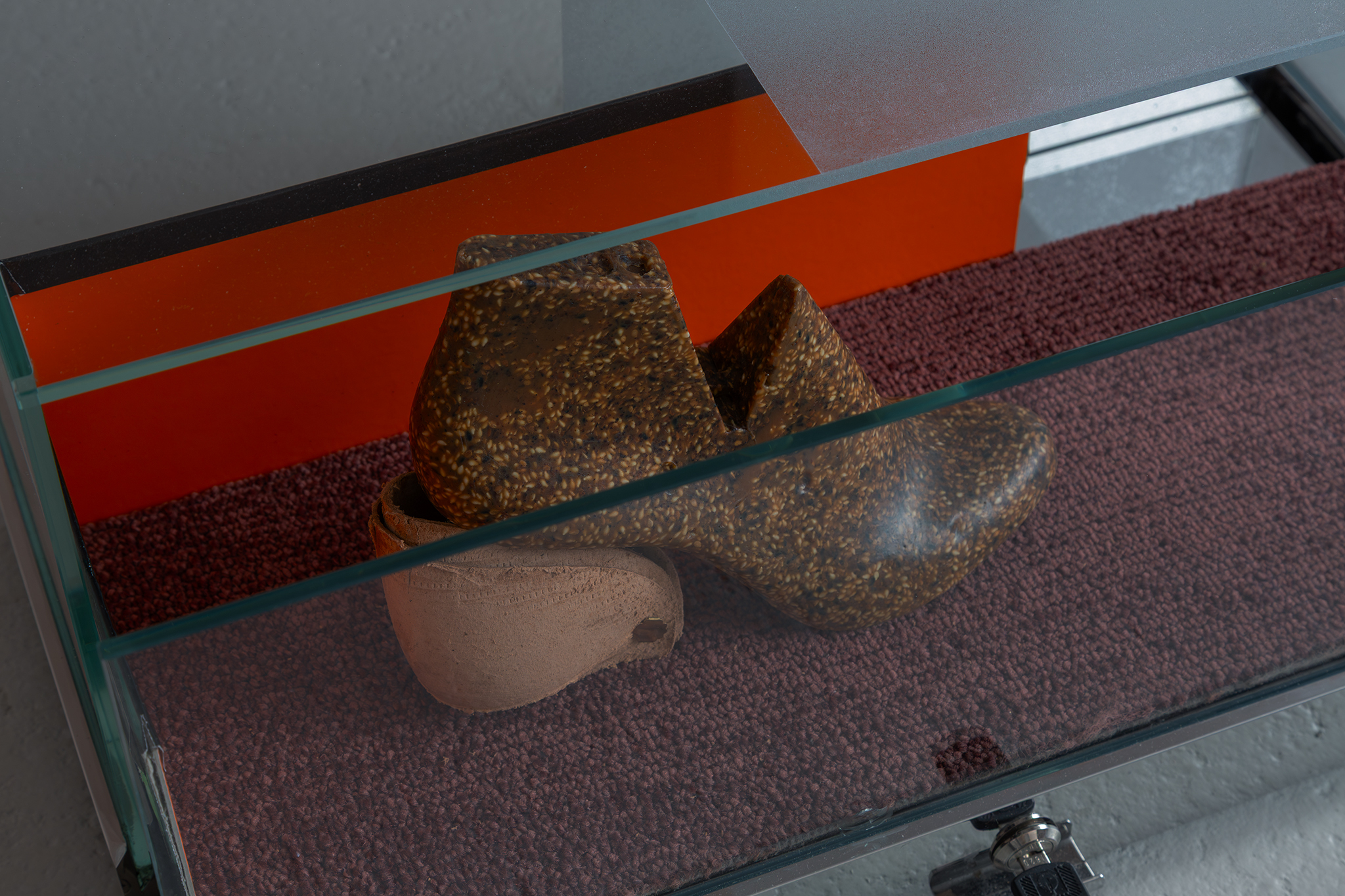 Maquette for an arid vision, 2026. Sesame in pine rosin and beeswax binder, carpet tile, cardboard shoe box and glass, frosted vinyl and stainless steel vitrine. S.A.D lamp, tulip ply and brown tape. Light programmed at the ratio of 2:1. Alia Hamaoui