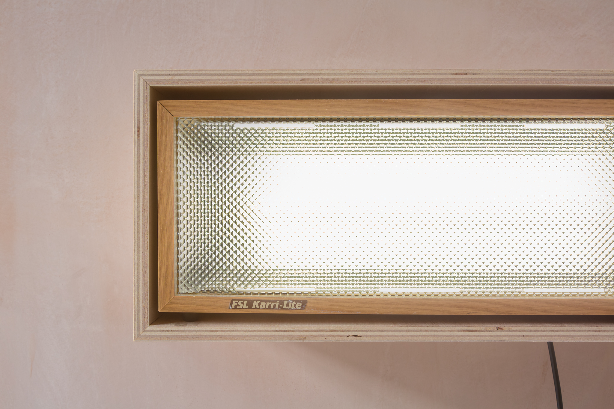 Maquette for an arid vision, 2026. Sesame in pine rosin and beeswax binder, carpet tile, cardboard shoe box and glass, frosted vinyl and stainless steel vitrine. S.A.D lamp, tulip ply and brown tape. Light programmed at the ratio of 2:1. Alia Hamaoui