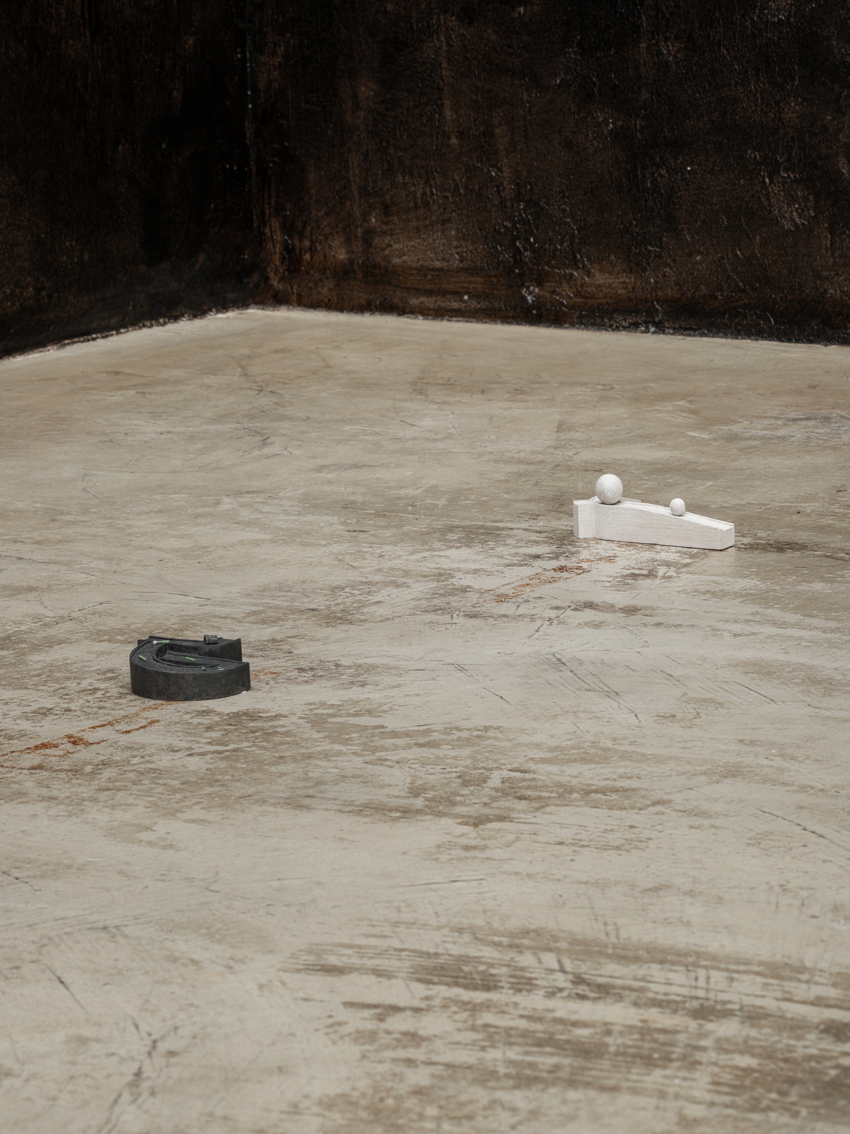 on the left: Kenji Ide, Night of Intrusion, 2026 Wood, water color, acrylic varnish, tape, 10 x 9 x 4 cm on the right: Kenji Ide, The slope with the sphere, 2026 Wood, water color, acrylic varnish, 15 x 8 x 6 cm