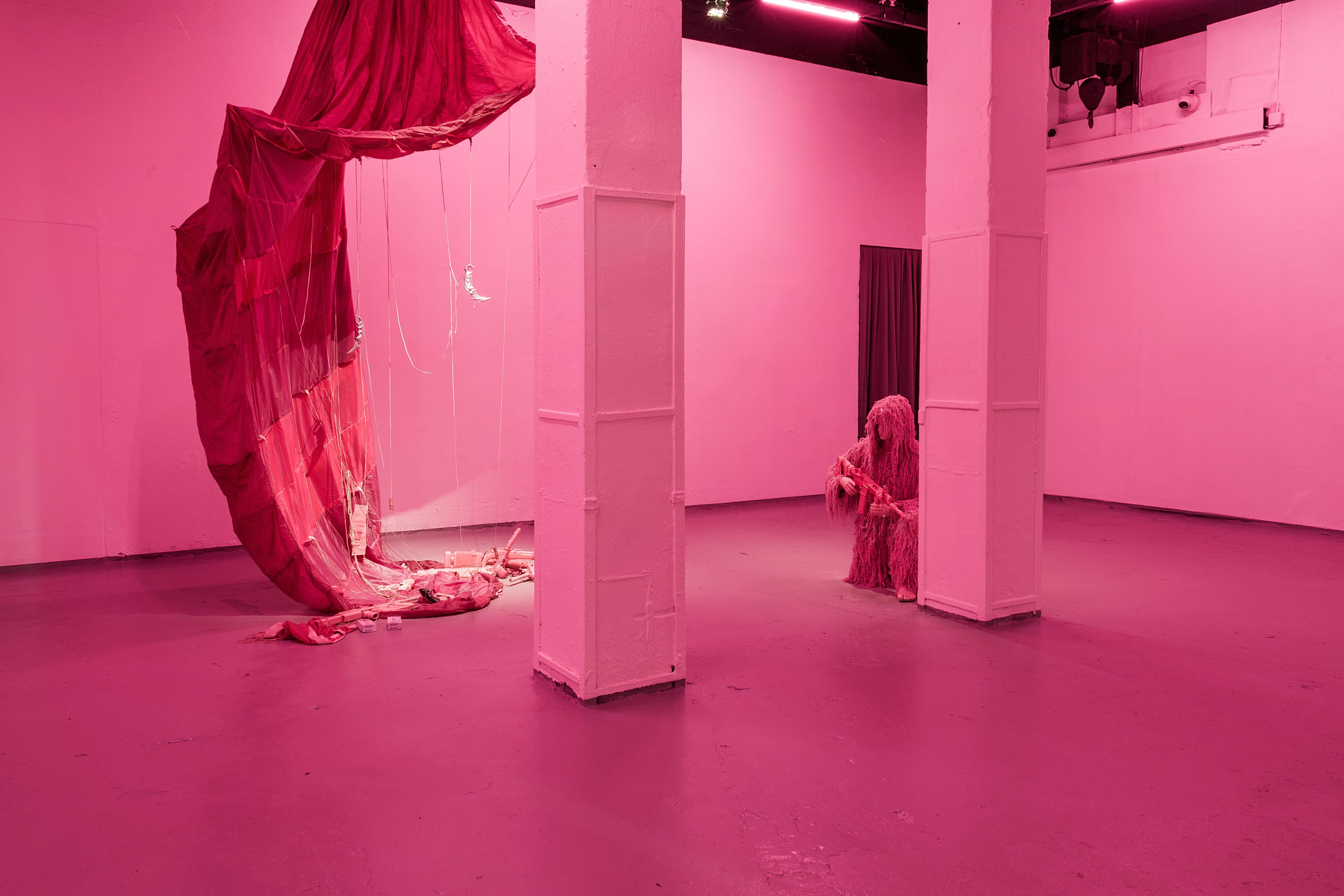 Keiu Maasik, Will I Die a Violent Death?, 2026. Spatial installation (plaster, metal, polyurethanene foam, ghillie suits, decorated 3D-printed weapon models and airsoft guns, redesigned cartridge boxes, used parachute canopy, video with sound). 
