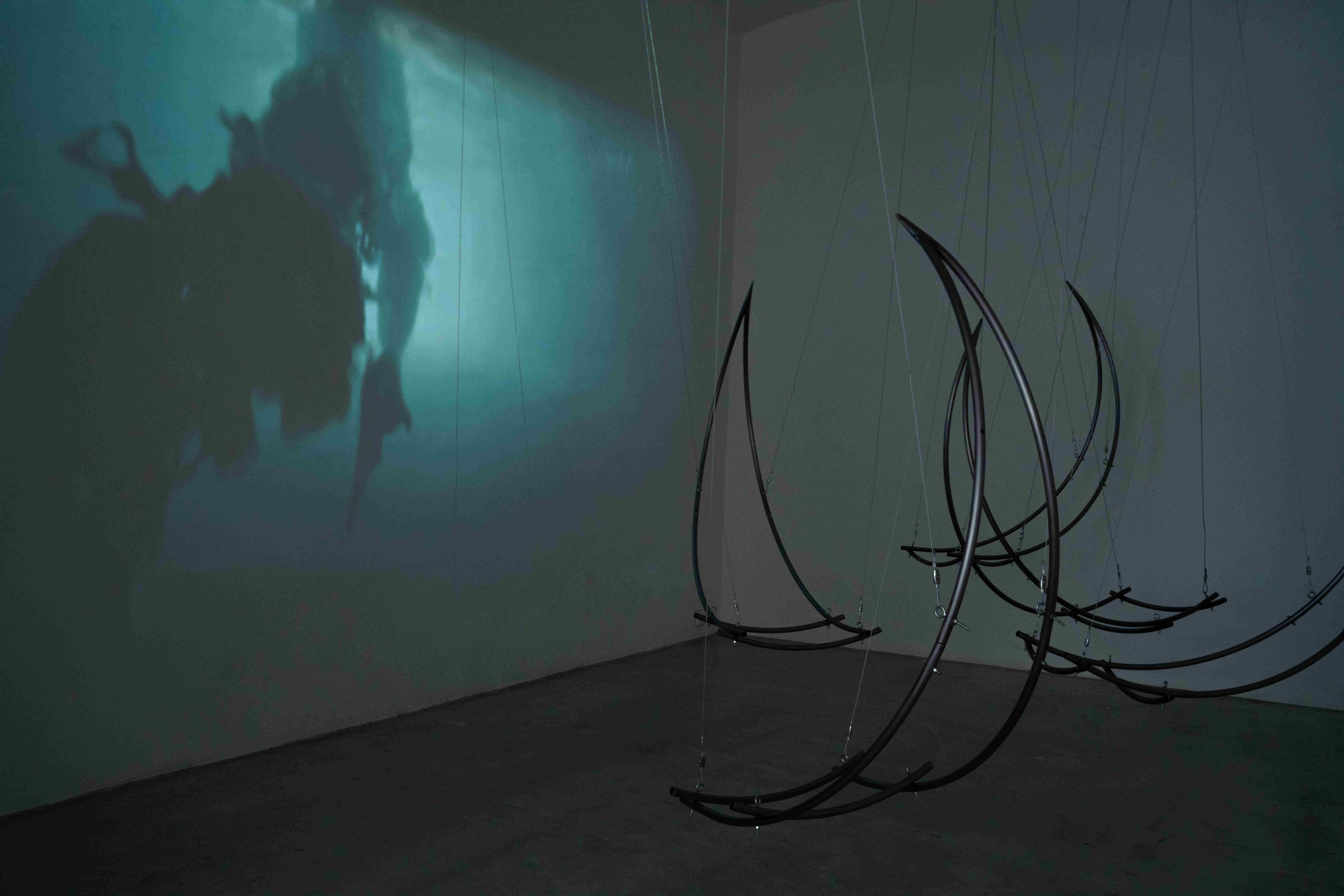 Agnes Questionmark, Exiled in Domestic Life. 2025. Single- channel video, Elena Rocabert, Balance Dependency. 2025 Curved iron, steel cable, metal couplings