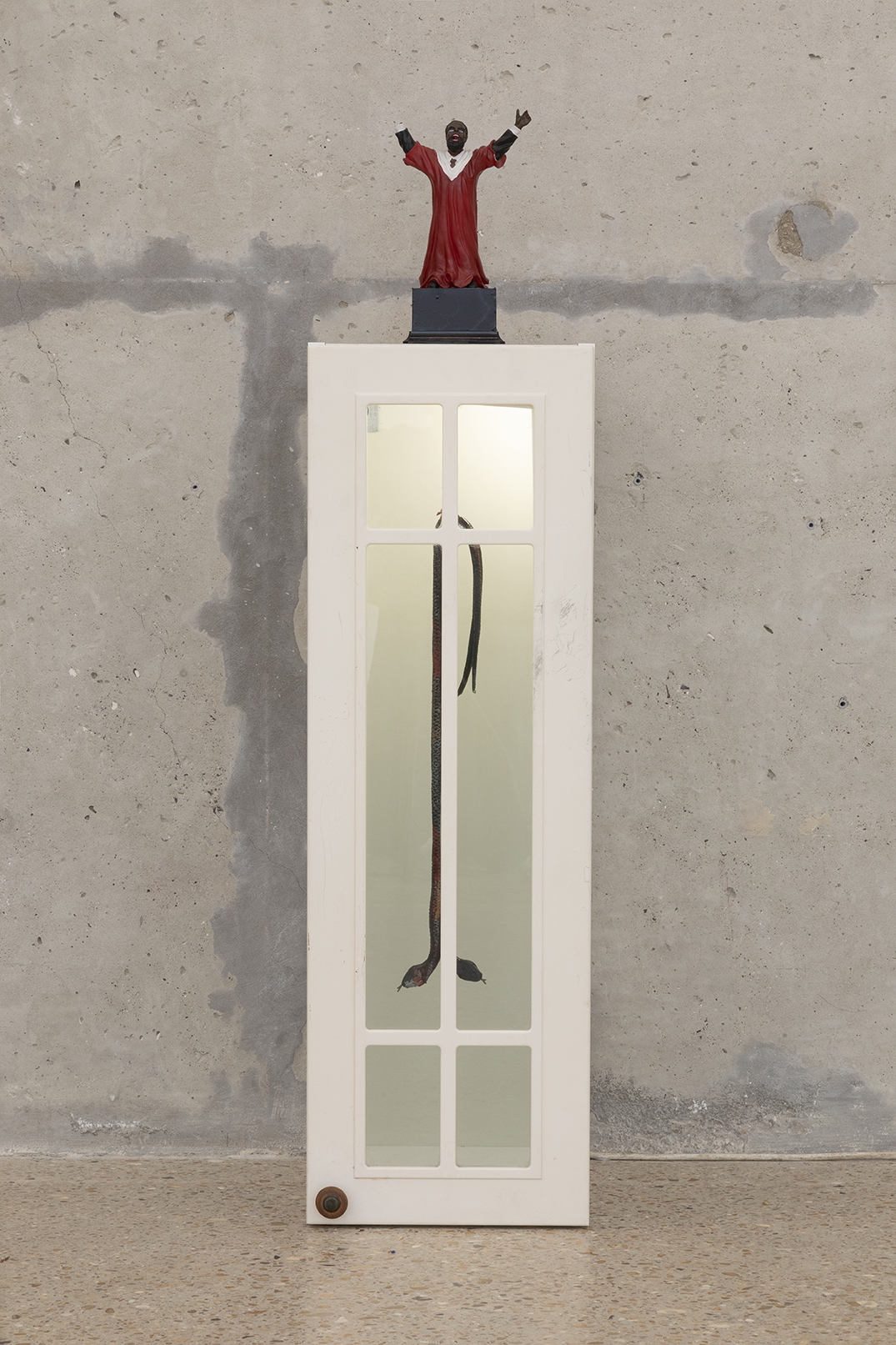 Ladji Diaby, First Stone, 2026, Statuette, fake snakes, kitchen cabinet, rope, stained-glass paint, 120 × 30 × 37,5 cm