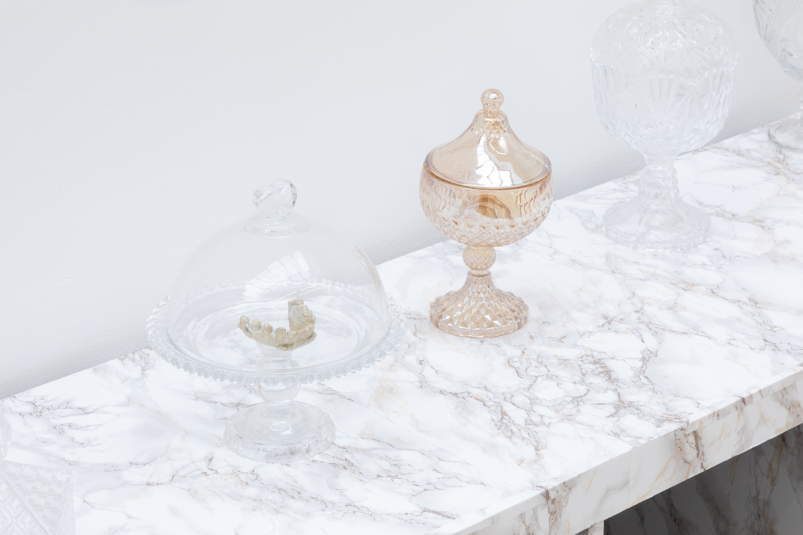 Ladji Diaby, Bud pot, 2026 (detail), Storage cabinet, glass candy jar, Hulk fists, skull, artificial flowers, marble-pattern adhesive paper, molded teeth, aerosol spray, 108 × 149 × 39 cm.