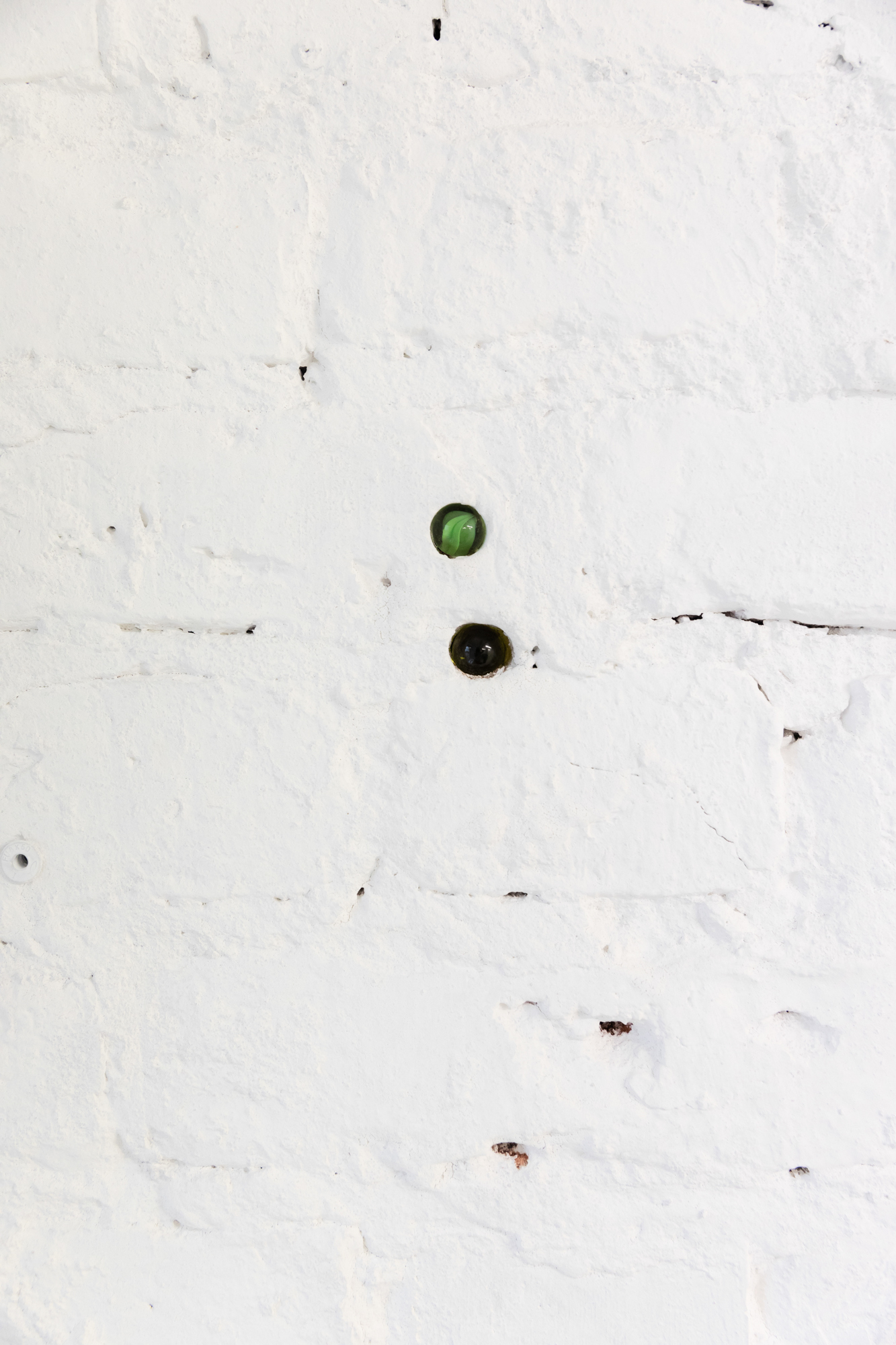 Krys Huba, eyes, 2026, glass marbles in the wall, various dimensions, in the exhibition falling into you, soft power, Berlin, 2026. Courtesy the artist and soft power, Berlin. Photo: Studio Replica.